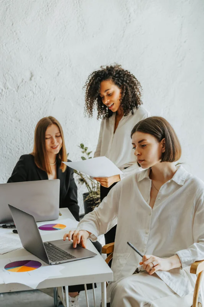 TEAM WORK - RAGAZZE CHE LAVORANO INSIEME ALLA STESSA SCRIVANIA SORRIDENDO